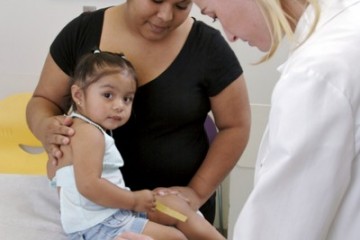 Physician examining child while mom watches