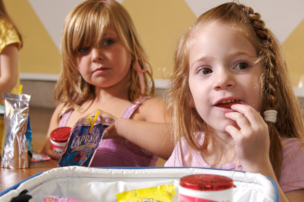 Two young girls eating lunch in pre-school