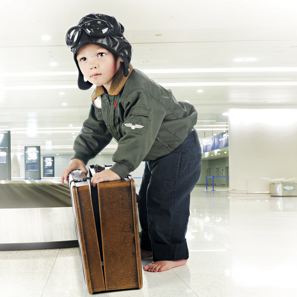 Young boy dressed like a pilot with suitcase at the airport