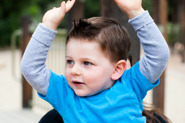Toddler boy with his arms raised in the air