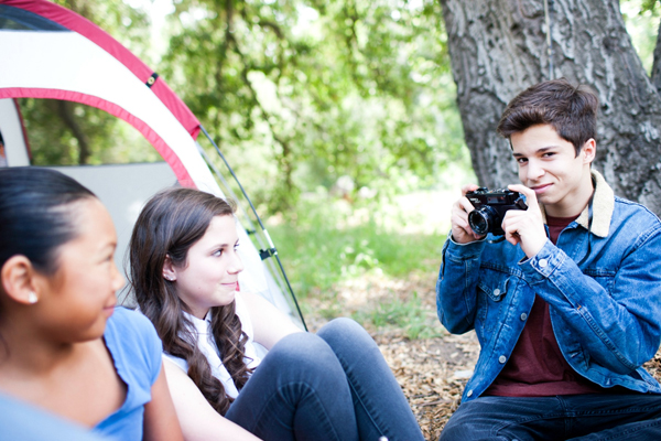 Teen boy with camera taking picture of his camping friends
