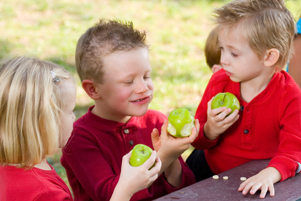 Three kids eating green apples