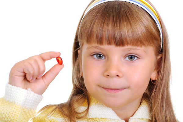 Young girl holding up a medicine capsule