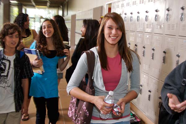 Smiling teen girl waling in the school hallway near the lockers