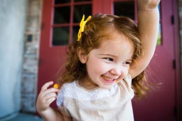 Smiling toddler girl with arm raised