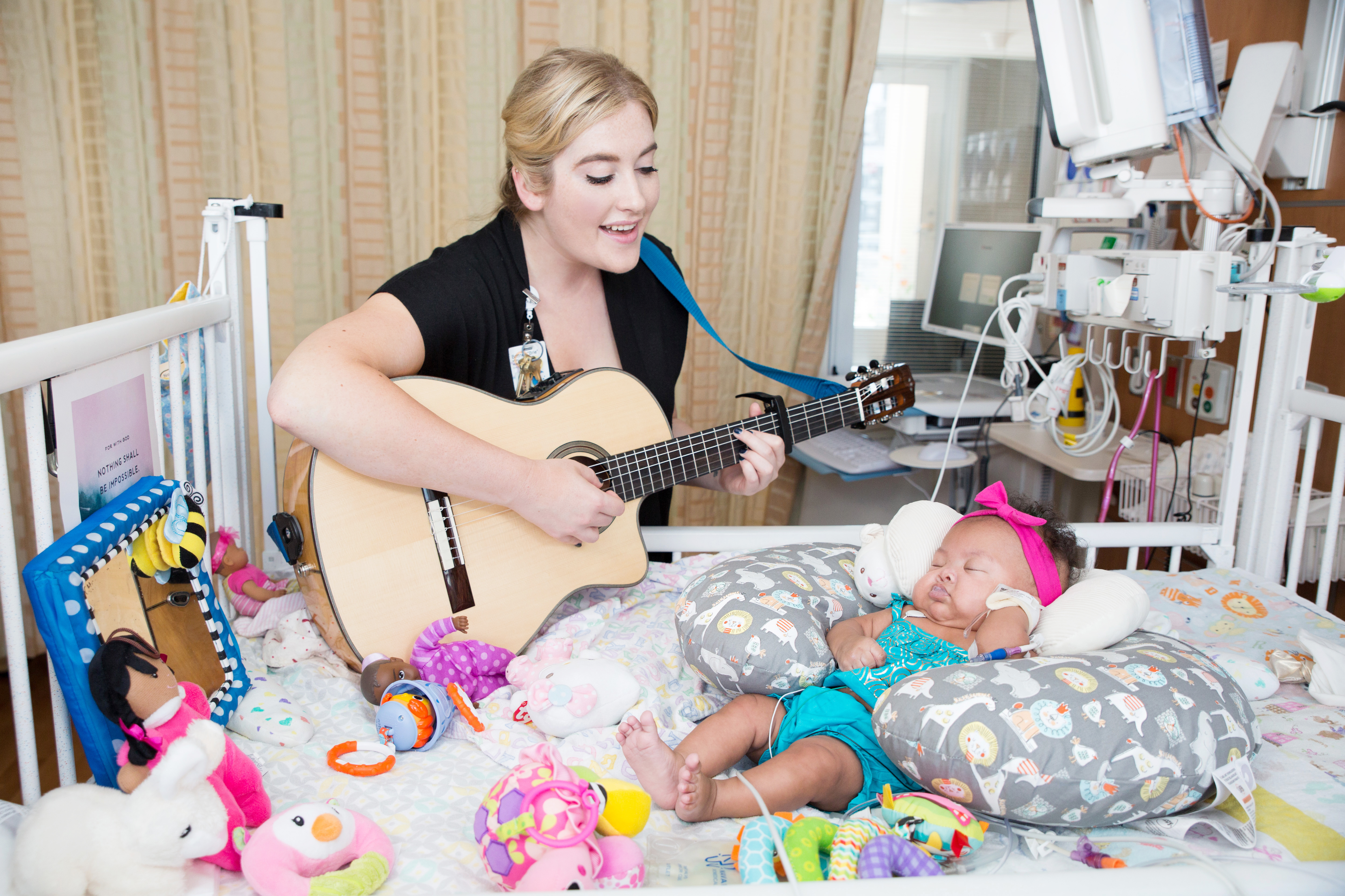 Music therapist with guitar singing to patient
