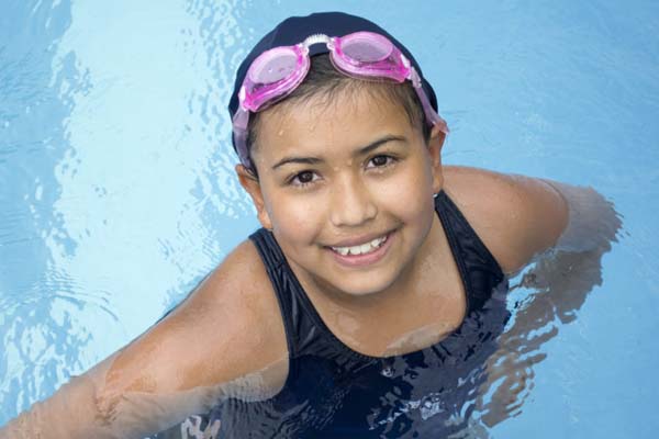 Young girl in the pool with pink goggles