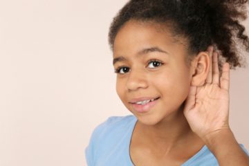 young girl holding hand against ear