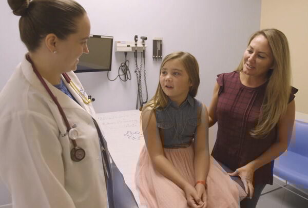 doctor with young patient and her mother in exam room