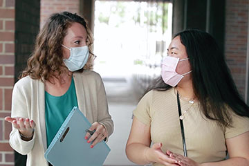 two masked physicians talking to one another