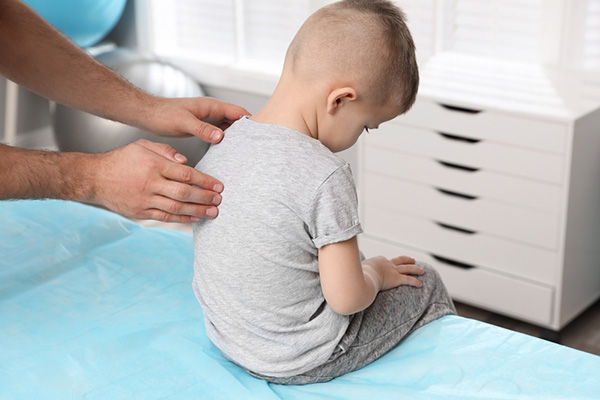 Young boy on exam table receives scoliosis screening test