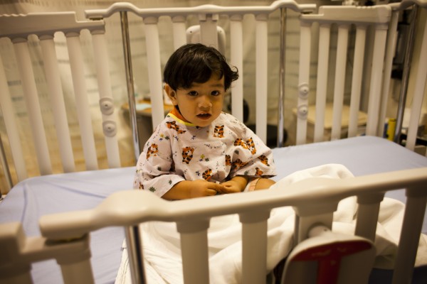 Little boy sitting in crib before surgery