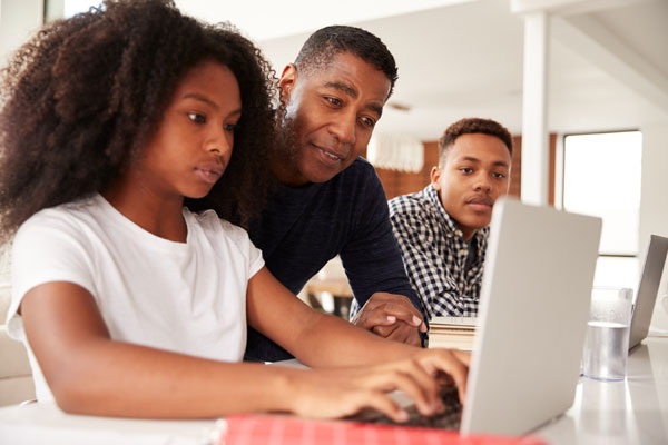 Teen girl looks at computer with family