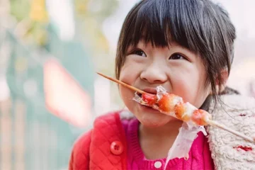 little girl eating a skewer