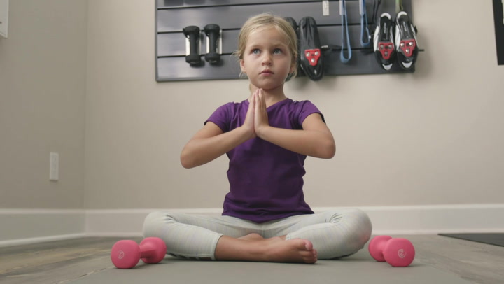 blonde girl sitting cross legged on a mat practicing yoga