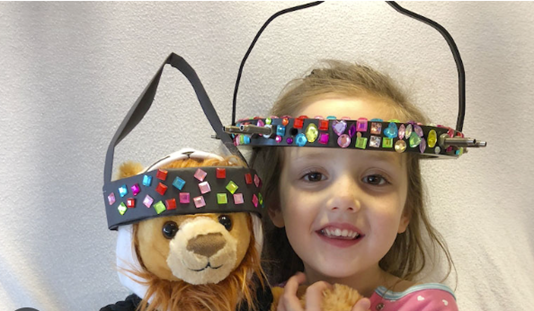 Young girl wears a scoliosis Halo next to her teddy bear, who also has a Halo