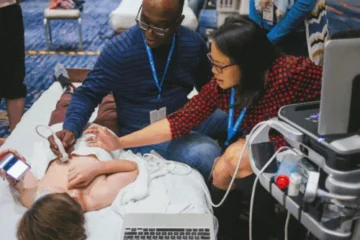 Medical professionals performing an ultrasound on a pediatric patient, demonstrating hands-on cardiac care techniques during a training session