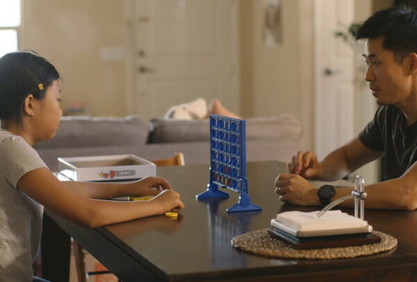child playing a game at a table with an adult