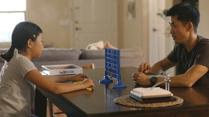 child playing a game at a table with an adult
