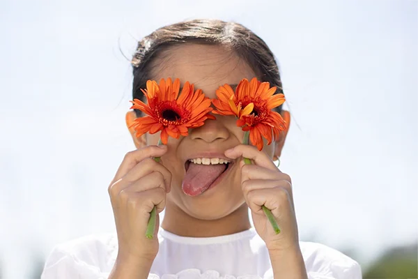 girl holding flowers over her eyes