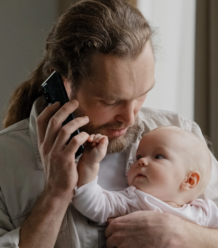 father on the phone holding his baby