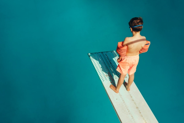 boy standing apprehensively on a diving board