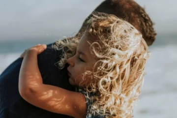 little girl hugging her dad on the beach