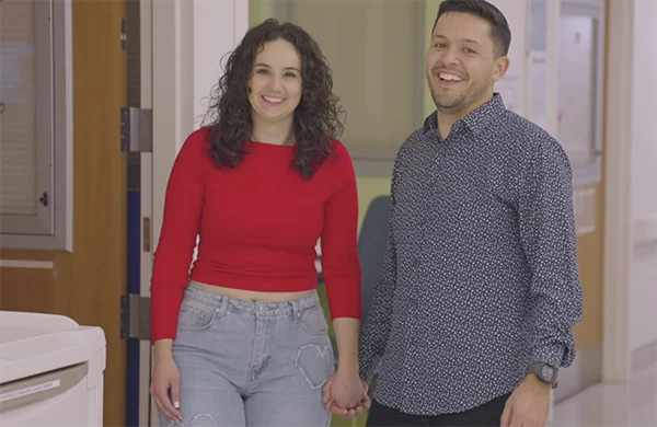 A couple holding hands and smiling in a hospital hallway