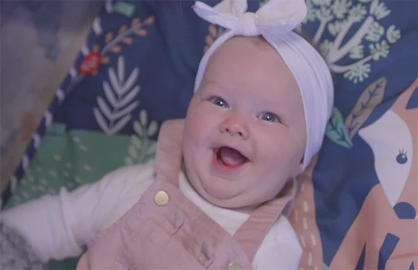 Smiling baby laying on a colorful backdrop.
