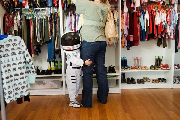 child dressed like astronaut holds mom's leg