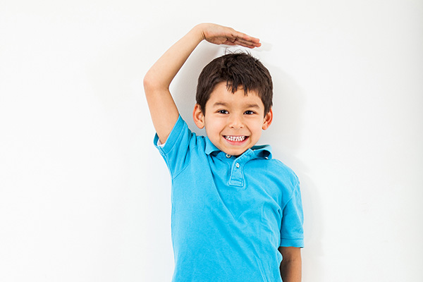 Child measuring himself and smiling - Help Me Grow OC