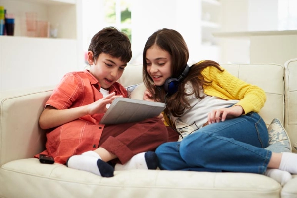 two children on the couch with an ipad