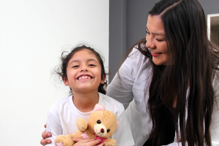 young girl holding teddy bear with doctor