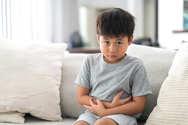 Child looks distressed and holds stomach